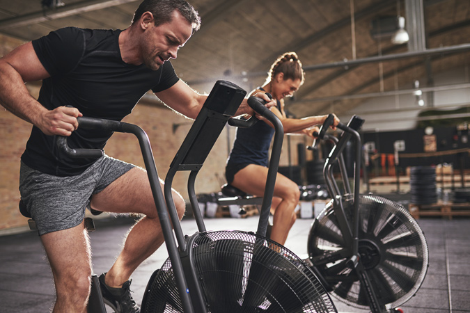 Man And Woman Exercising On An Exercise Bike