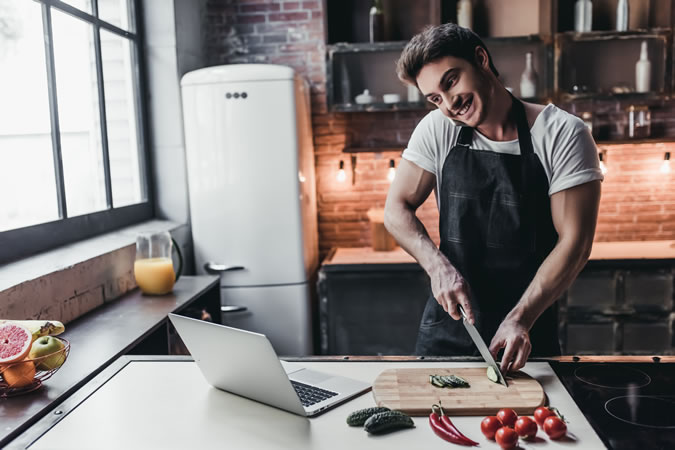 Man Cooking And Looking At A Laptop