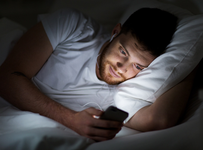 Man Using His Phone In Bed