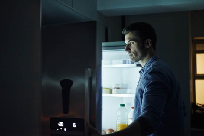 Man opening a fridge at night